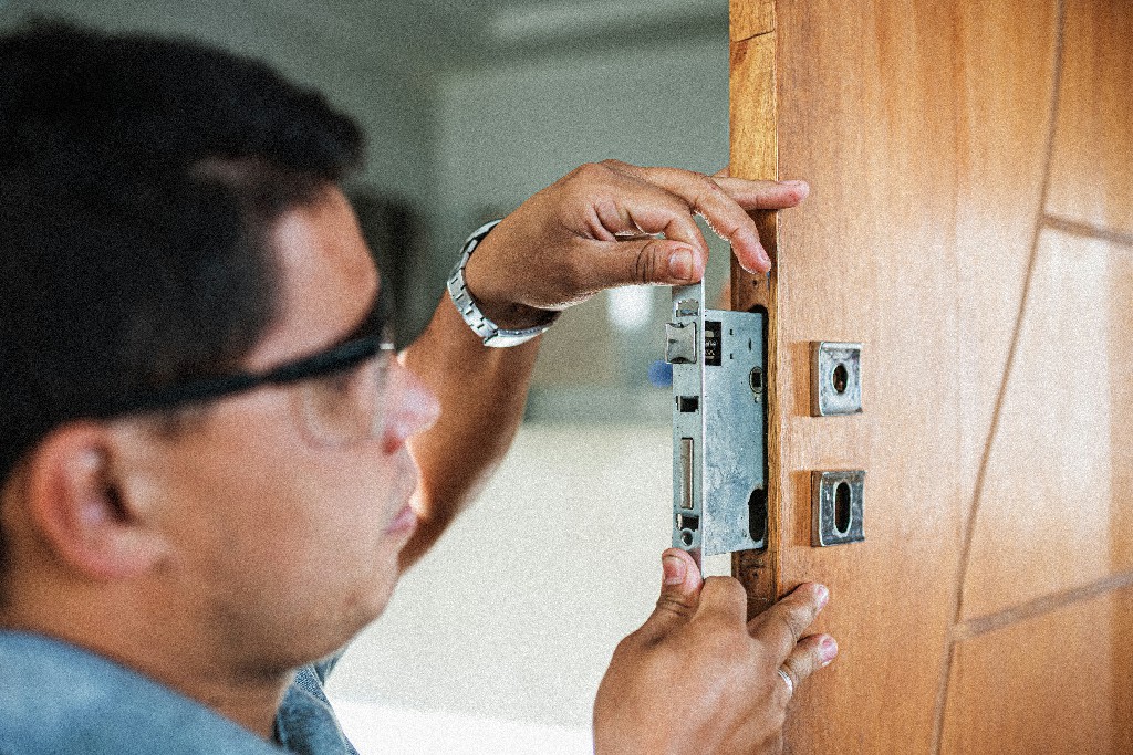 Close-up of male hands repair or installing a metal door lock.